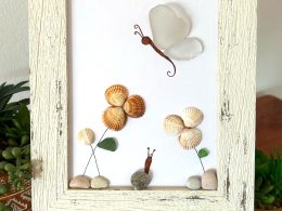 A lovely scene with a butterfly, snail, and flowers, made with seaglass and seashells, perfect as a unique gift!